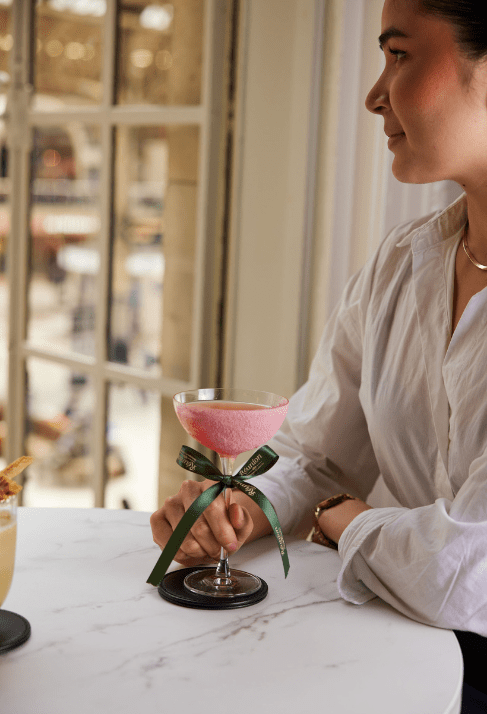 Person holding a pink cocktail overlooking Victoria Station