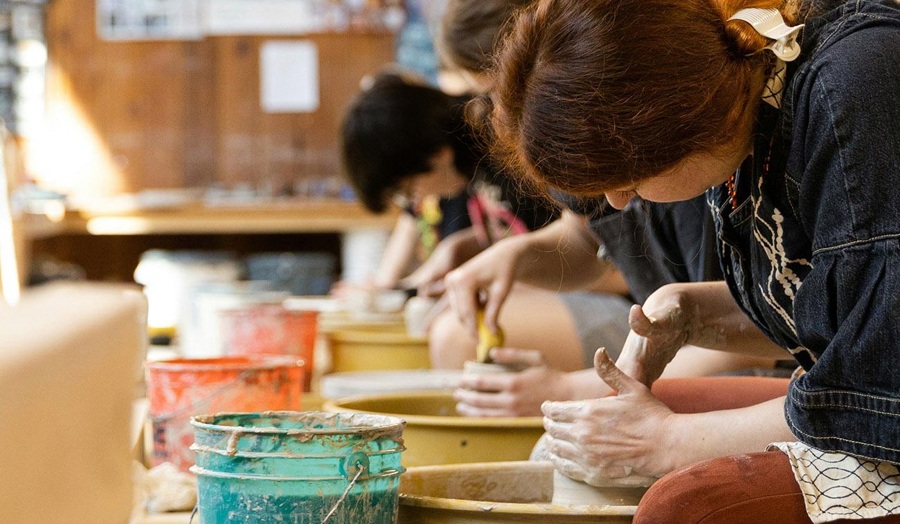 A group of people shaping pottery on a wheel