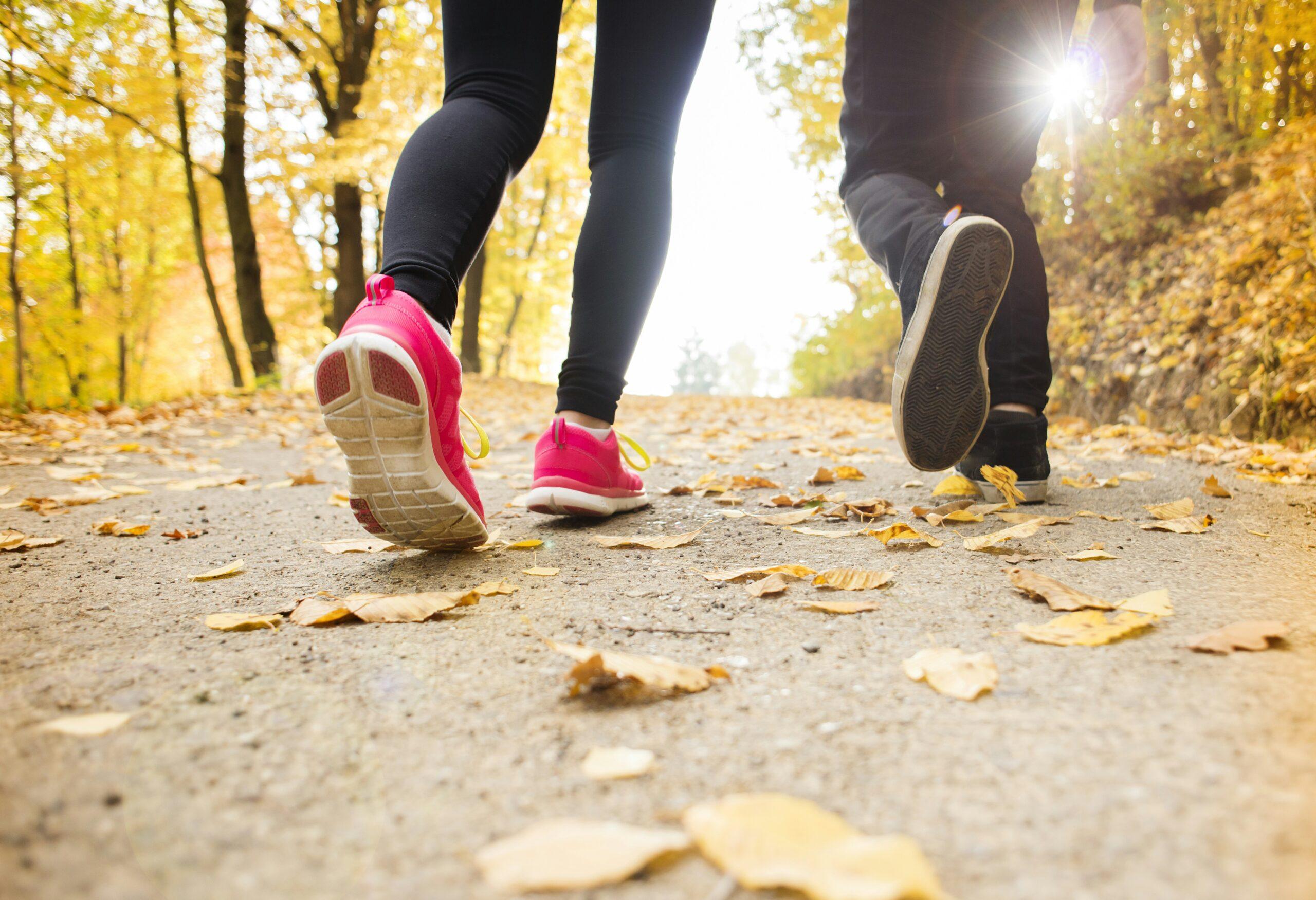 Close up of feet walking on autumn leaves in a park