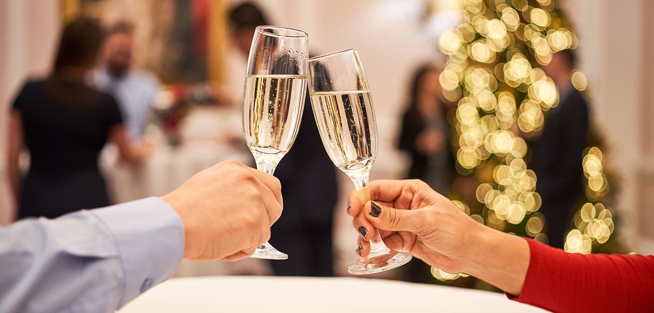 A close up of Champagne glasses with people in the background socialising